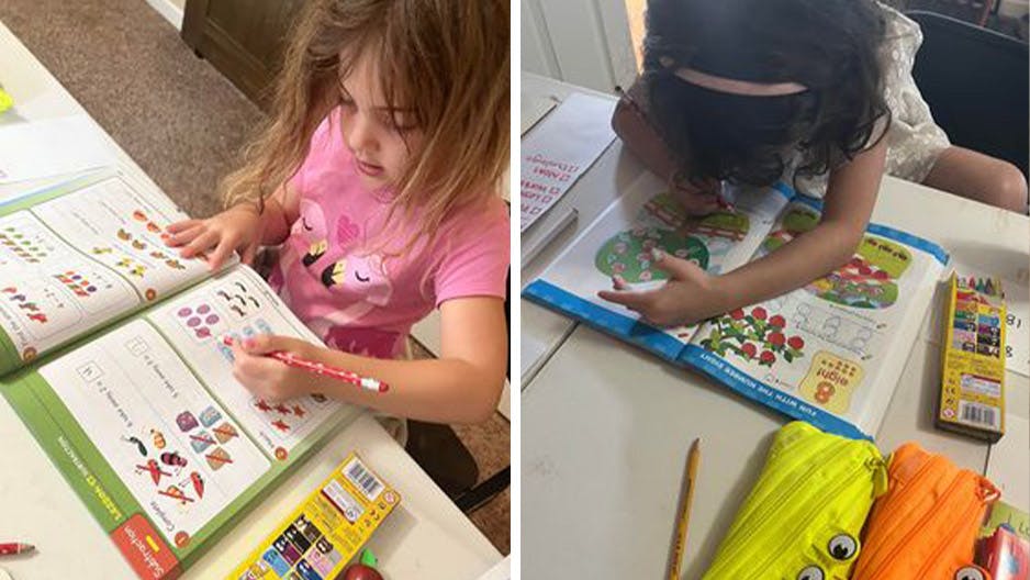 Two kindergarten girls homeschool with ABC Reading Eggs workbooks.